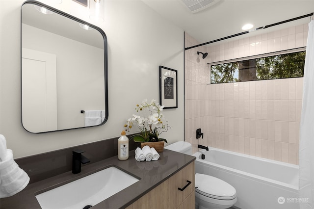 full bathroom featuring tiled shower / bath, vanity, and toilet