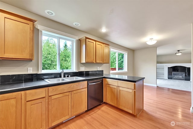 kitchen featuring stainless steel dishwasher, kitchen peninsula, sink, and light hardwood / wood-style floors