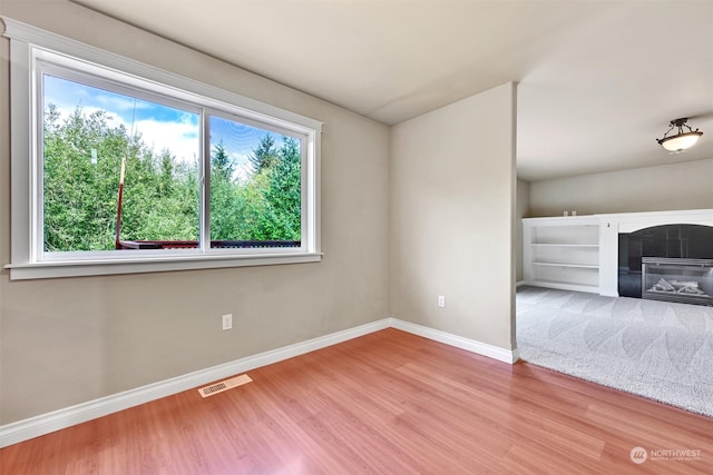 unfurnished bedroom featuring multiple windows, a tile fireplace, and hardwood / wood-style flooring