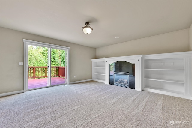 unfurnished living room with built in shelves and carpet