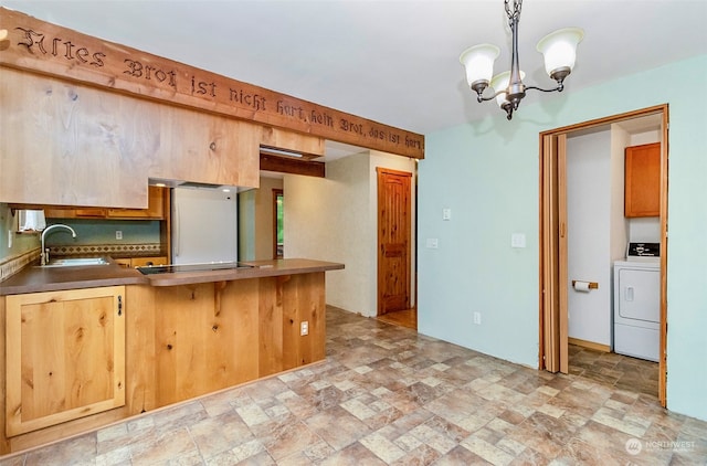 kitchen with pendant lighting, sink, washer / dryer, a breakfast bar, and an inviting chandelier