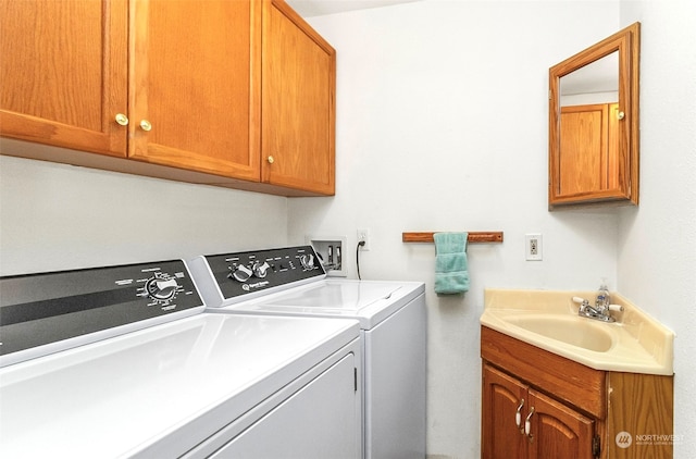 washroom with washing machine and clothes dryer, cabinets, and sink