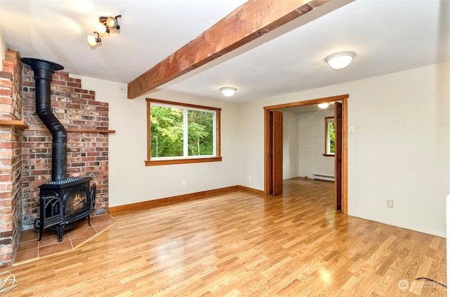 unfurnished living room with light wood-type flooring, beam ceiling, baseboard heating, and a wood stove