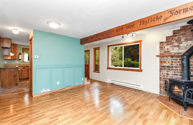 living room featuring light hardwood / wood-style flooring, beam ceiling, a wood stove, and a baseboard heating unit