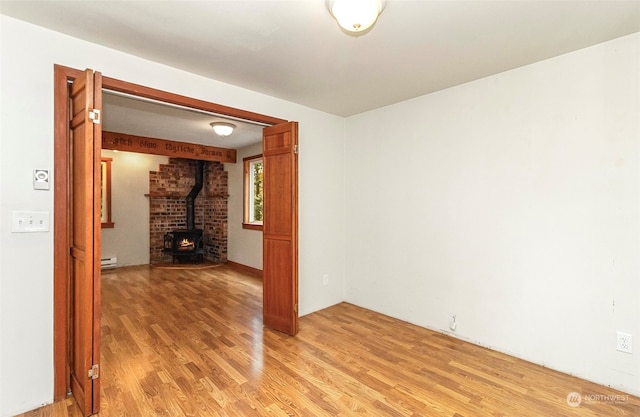 unfurnished room featuring hardwood / wood-style floors and a wood stove