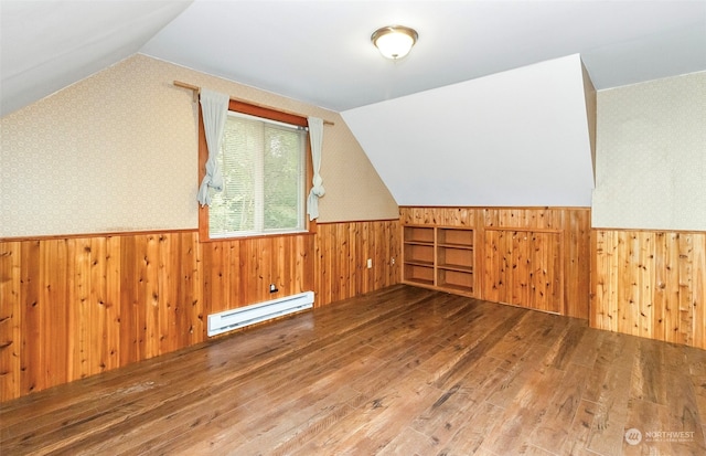 bonus room featuring wooden walls, wood-type flooring, vaulted ceiling, and a baseboard heating unit