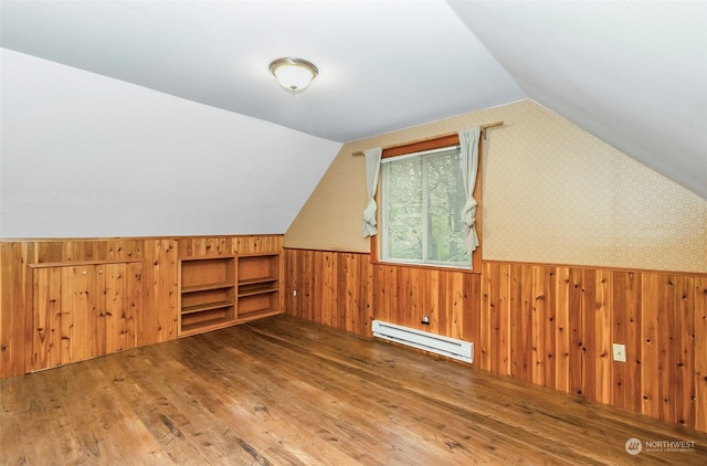 additional living space with dark hardwood / wood-style floors, lofted ceiling, wood walls, and baseboard heating