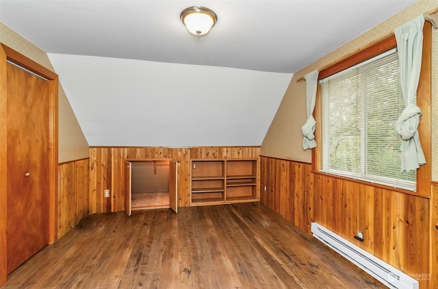 additional living space featuring a baseboard heating unit, vaulted ceiling, wood walls, and dark hardwood / wood-style flooring