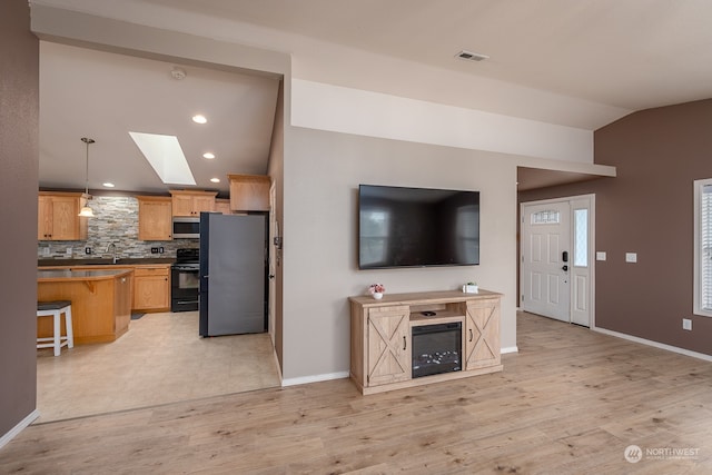 living room with lofted ceiling with skylight and light hardwood / wood-style flooring