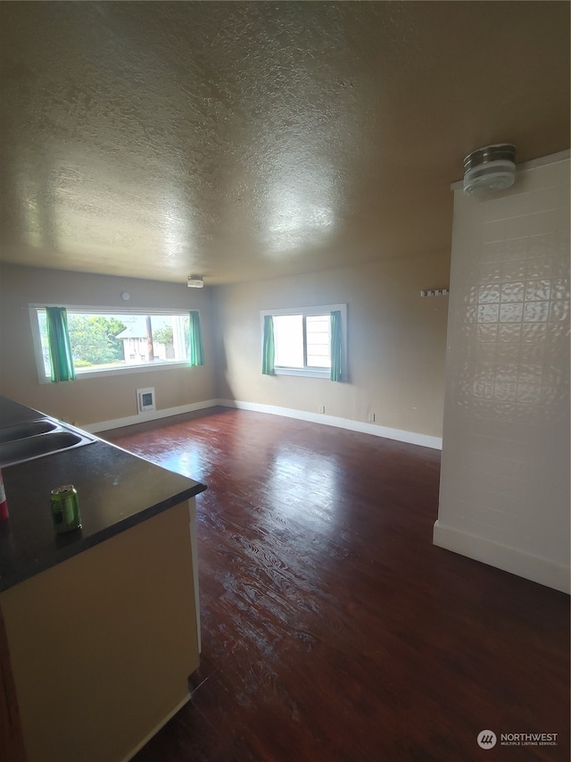 empty room featuring a textured ceiling, plenty of natural light, sink, and dark hardwood / wood-style flooring