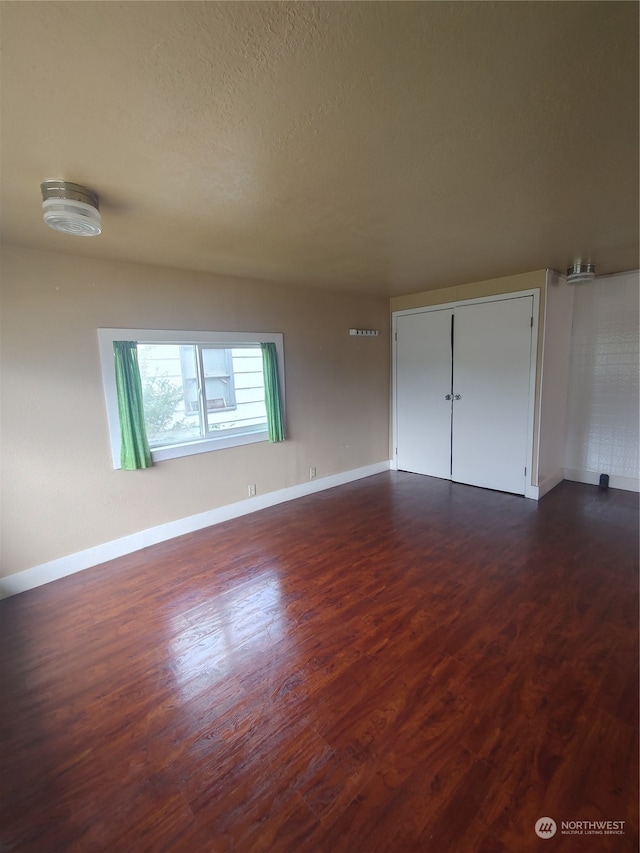 unfurnished bedroom with a closet, dark hardwood / wood-style floors, and a textured ceiling