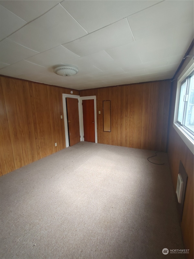 carpeted spare room featuring wooden walls