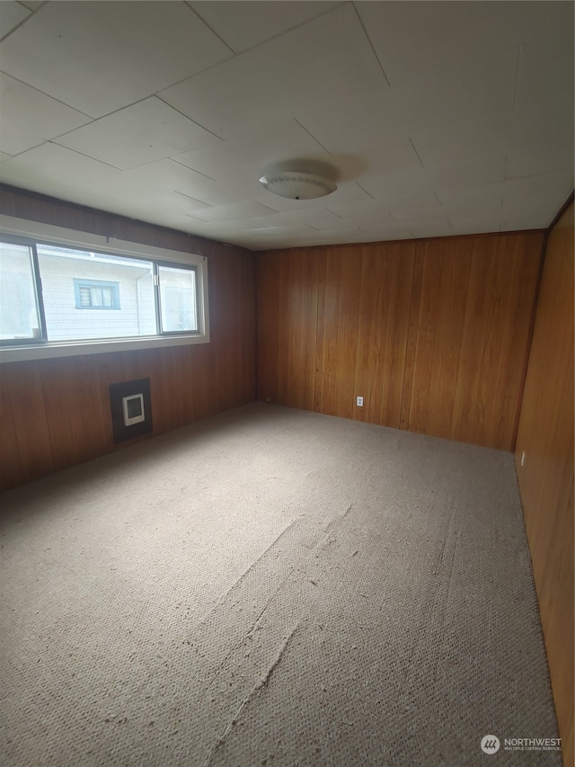 carpeted spare room featuring wood walls