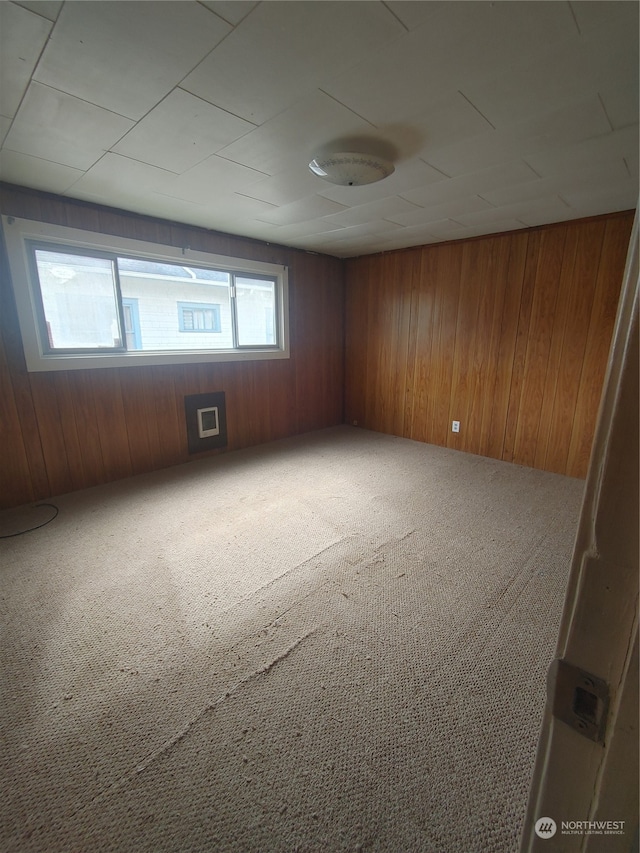 carpeted spare room with wood walls