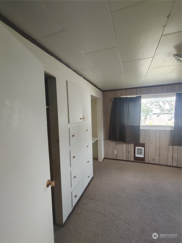 unfurnished bedroom with wood walls and carpet floors