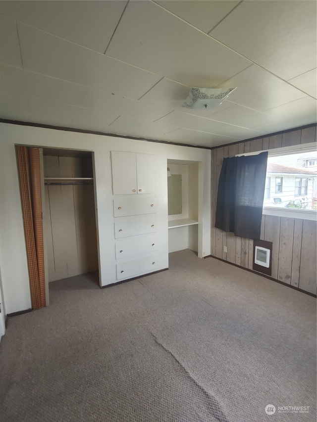 unfurnished bedroom with wood walls and light colored carpet