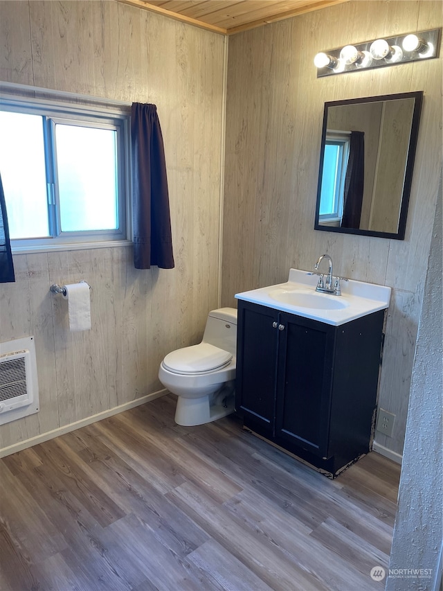 bathroom featuring hardwood / wood-style floors, vanity, wooden walls, and toilet