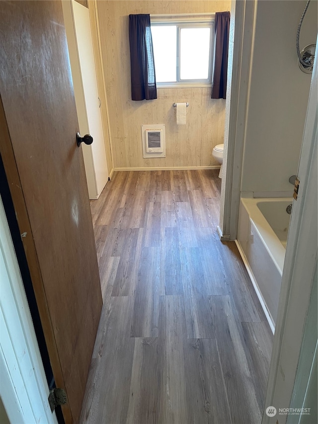 bathroom featuring hardwood / wood-style flooring, a tub, toilet, and heating unit