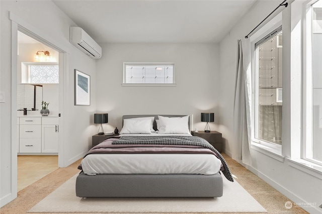 bedroom featuring light carpet, a wall unit AC, and ensuite bath