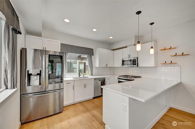 kitchen featuring pendant lighting, white cabinets, stainless steel appliances, sink, and kitchen peninsula