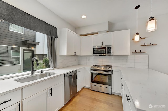 kitchen with decorative backsplash, white cabinetry, appliances with stainless steel finishes, and pendant lighting