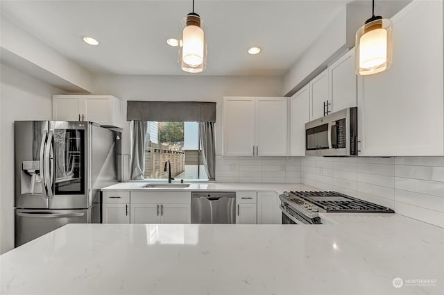 kitchen with sink, white cabinetry, hanging light fixtures, and stainless steel appliances