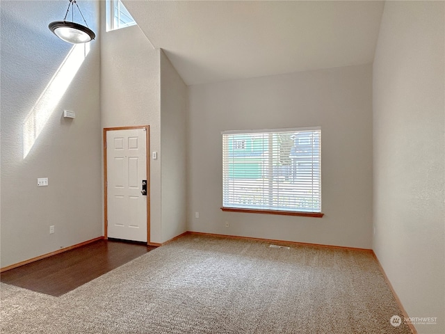 carpeted empty room featuring lofted ceiling and plenty of natural light