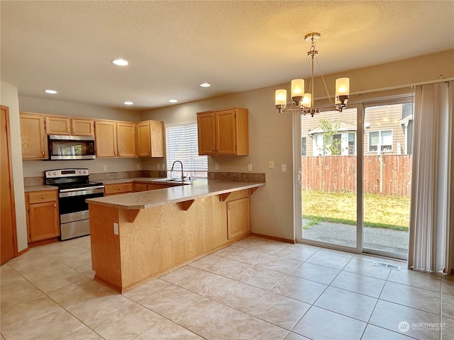 kitchen featuring pendant lighting, kitchen peninsula, sink, appliances with stainless steel finishes, and a breakfast bar area