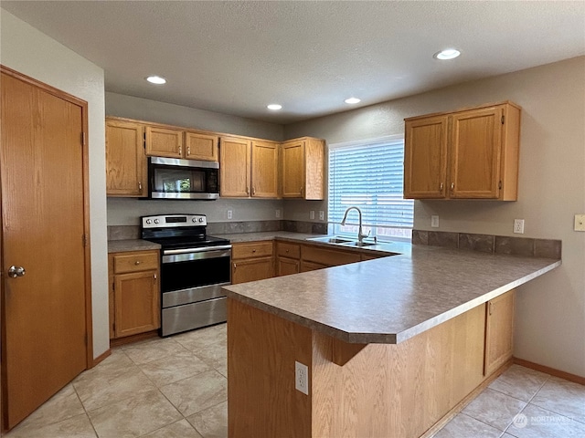 kitchen featuring a textured ceiling, light tile patterned floors, appliances with stainless steel finishes, kitchen peninsula, and sink