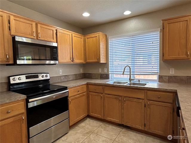 kitchen featuring light tile patterned floors, stainless steel appliances, and sink