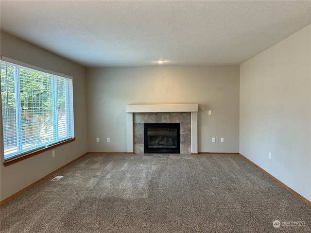 unfurnished living room with a fireplace, a textured ceiling, and carpet flooring