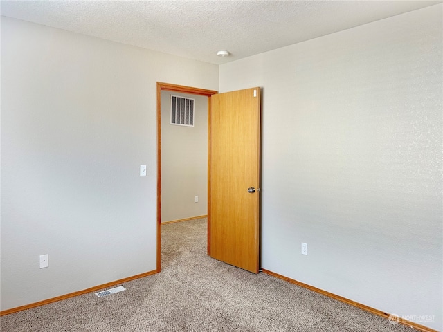 spare room with light carpet and a textured ceiling