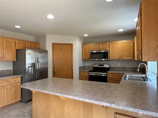 kitchen with a textured ceiling, appliances with stainless steel finishes, kitchen peninsula, sink, and light tile patterned flooring