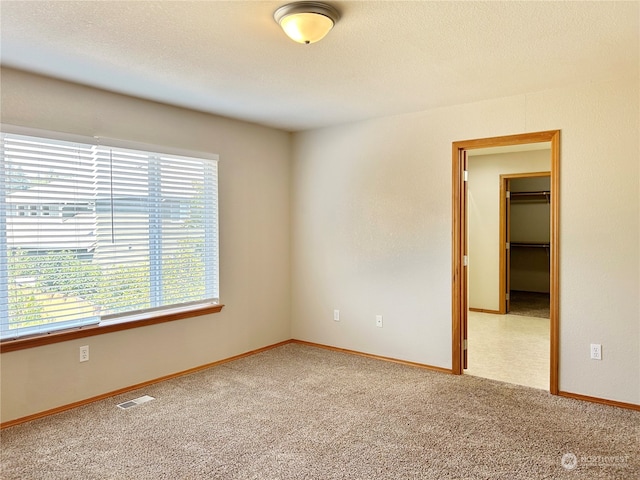 carpeted empty room featuring plenty of natural light and a textured ceiling