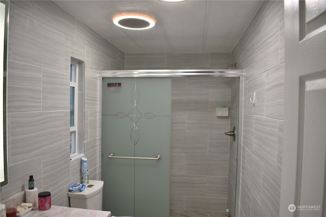 bathroom featuring a shower with door and toilet