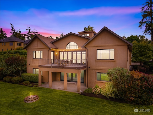 back house at dusk with an outdoor fire pit, a yard, and a patio area