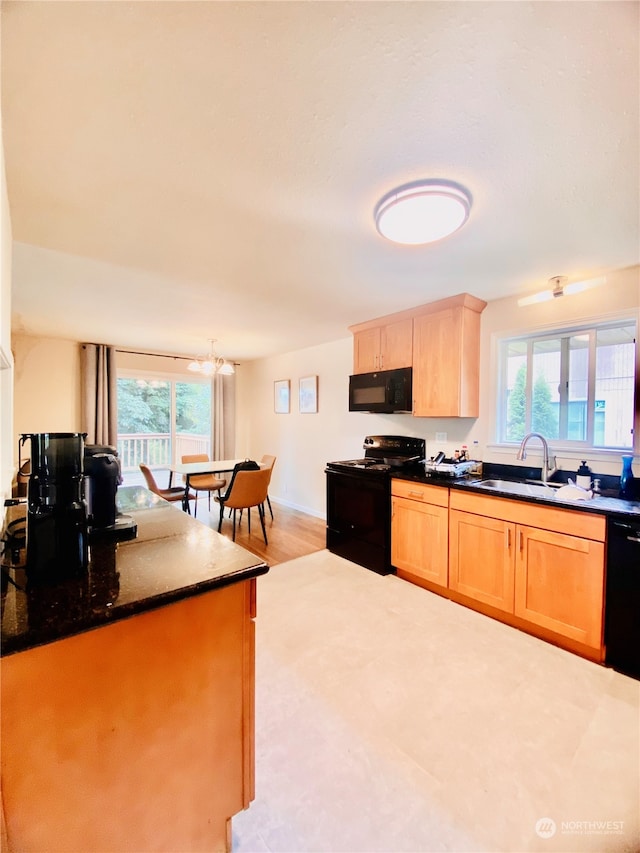 kitchen featuring a healthy amount of sunlight, black appliances, light hardwood / wood-style flooring, and sink