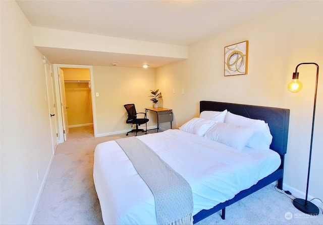 bedroom with a closet, a spacious closet, and light carpet