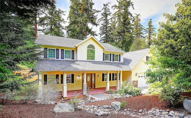 view of front of house with an attached garage, covered porch, and roof with shingles