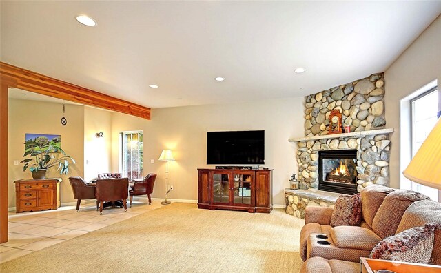 living room with beamed ceiling, a stone fireplace, and tile patterned floors