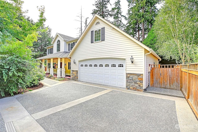 view of front of property with aphalt driveway, a garage, fence, and stone siding