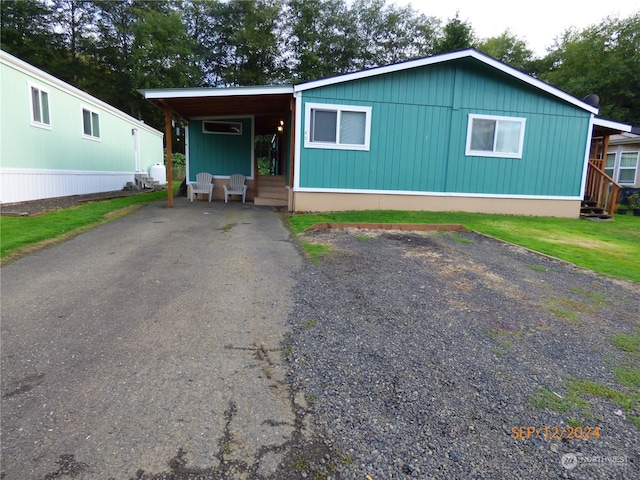 manufactured / mobile home featuring a front yard and a carport