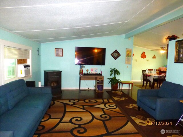 living room featuring cooling unit, a wood stove, vaulted ceiling with beams, ceiling fan, and a textured ceiling