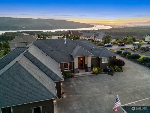 aerial view at dusk featuring a water and mountain view