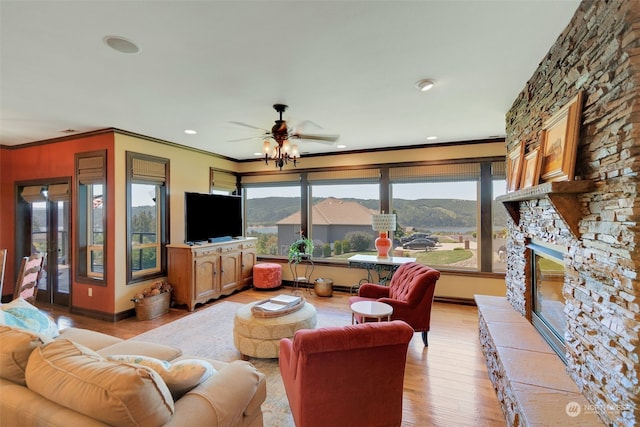 living room with crown molding, a fireplace, ceiling fan, and light hardwood / wood-style flooring