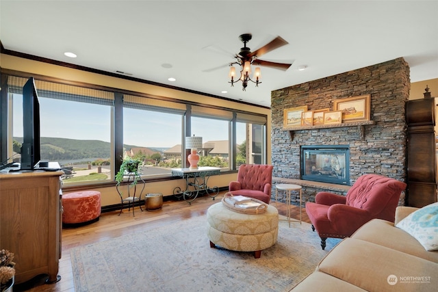 living room with wood-type flooring, a fireplace, crown molding, and ceiling fan