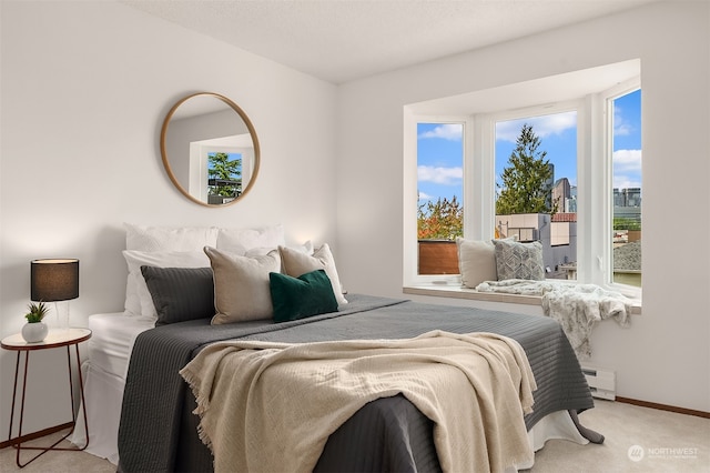 bedroom with a baseboard heating unit and light colored carpet