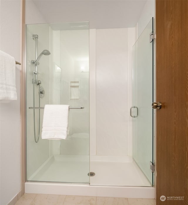 bathroom with a shower with door and tile patterned floors