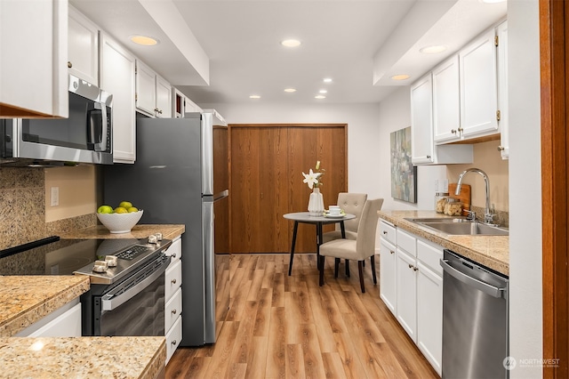 kitchen with stainless steel appliances, sink, light wood-type flooring, and white cabinets