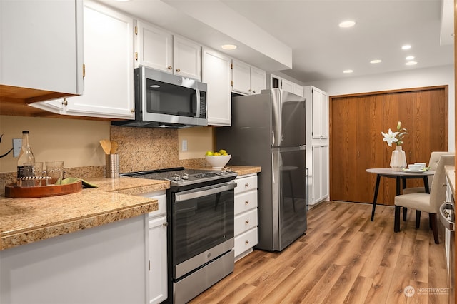 kitchen featuring light wood-type flooring, backsplash, stainless steel appliances, and white cabinetry